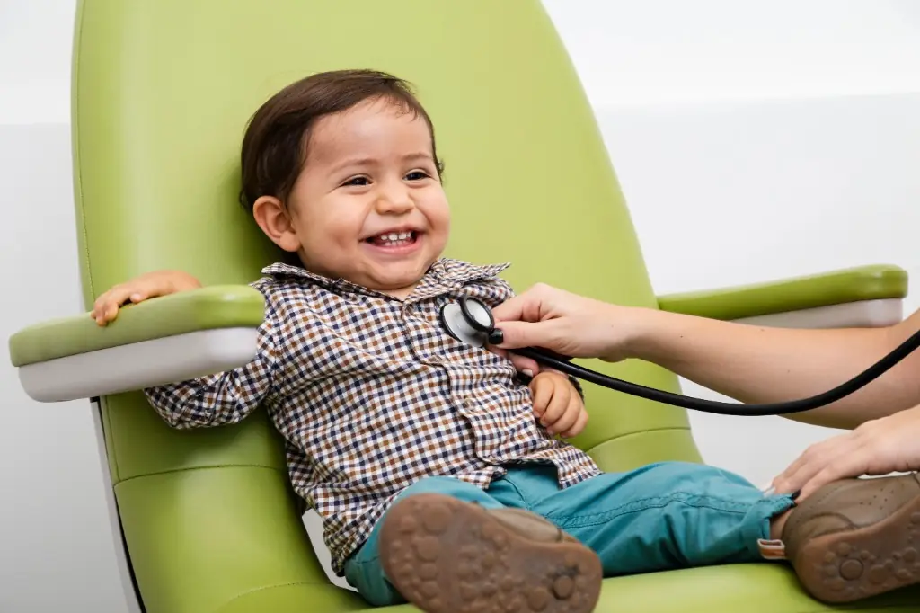 Smiling toddler on an exam chair during a paediatric checkup at Tiny Totz Kids Clinic in Puppalguda, Hyderabad